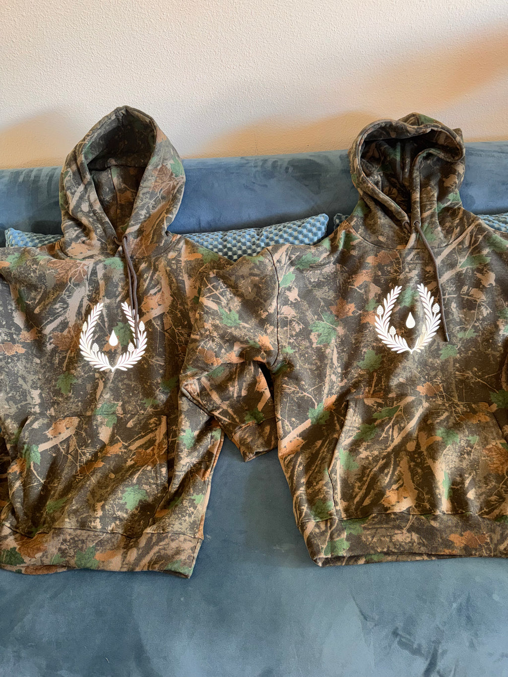 Silent Signal camo hoodie with reflective laurel crest emblem — detail view