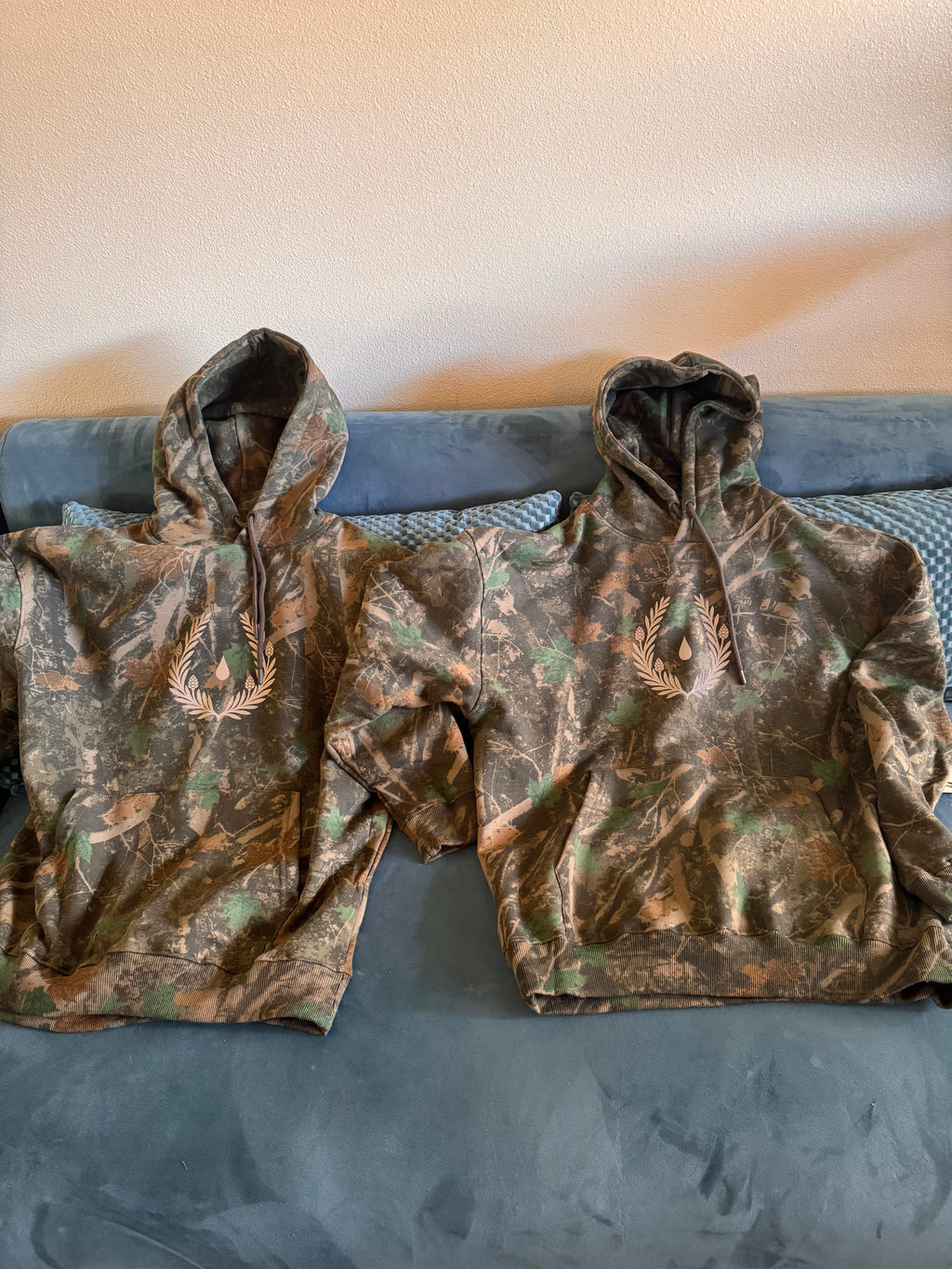 Silent Signal camo hoodie with reflective laurel crest emblem — front view