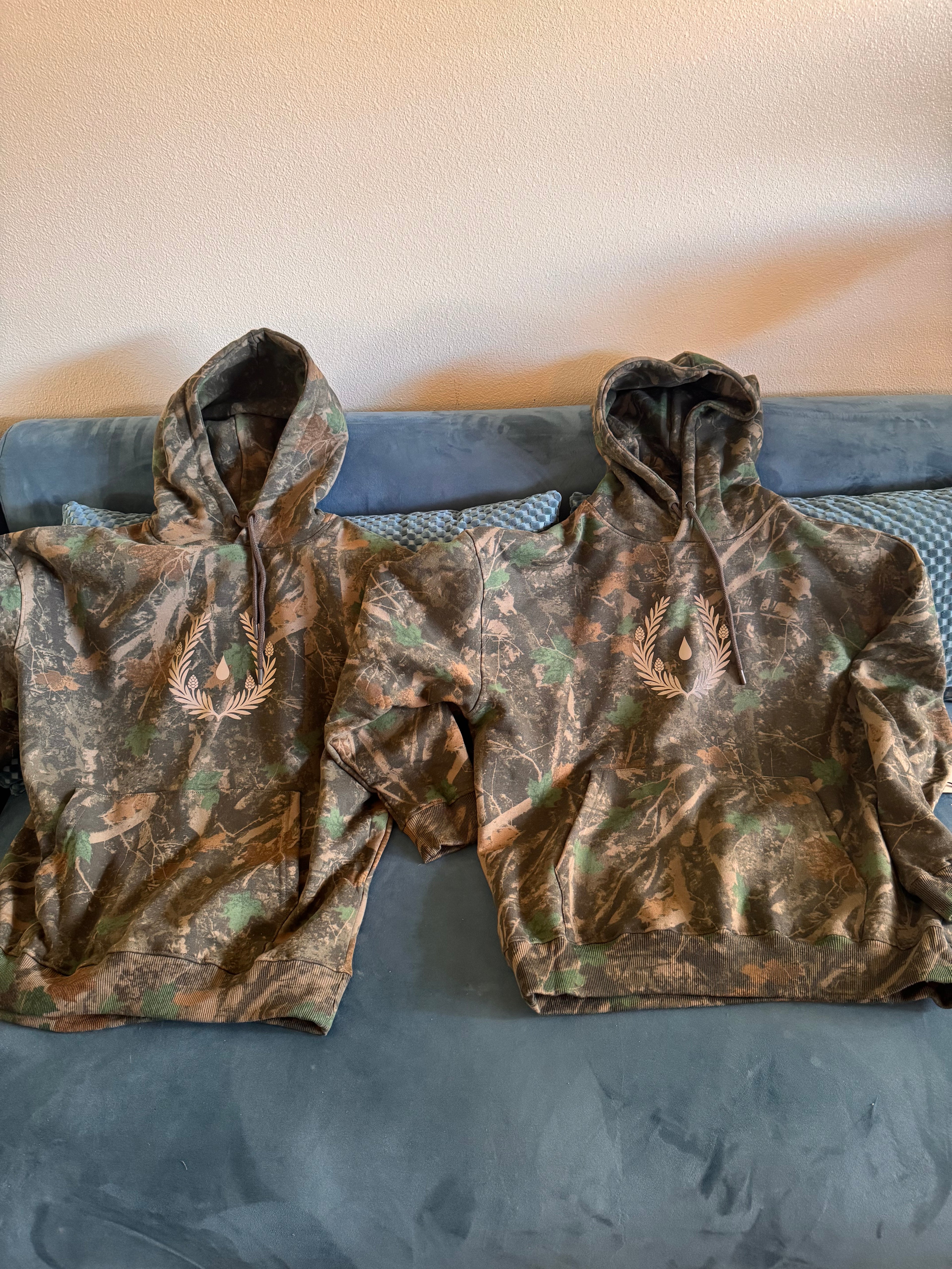 Silent Signal camo hoodie with reflective laurel crest emblem — front view